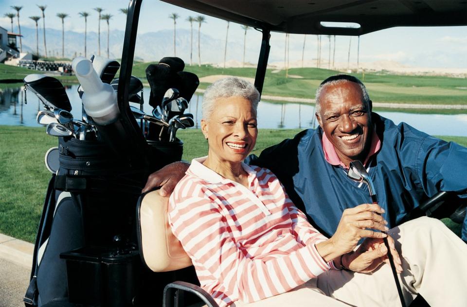 Smiling couple sitting in a golf cart.